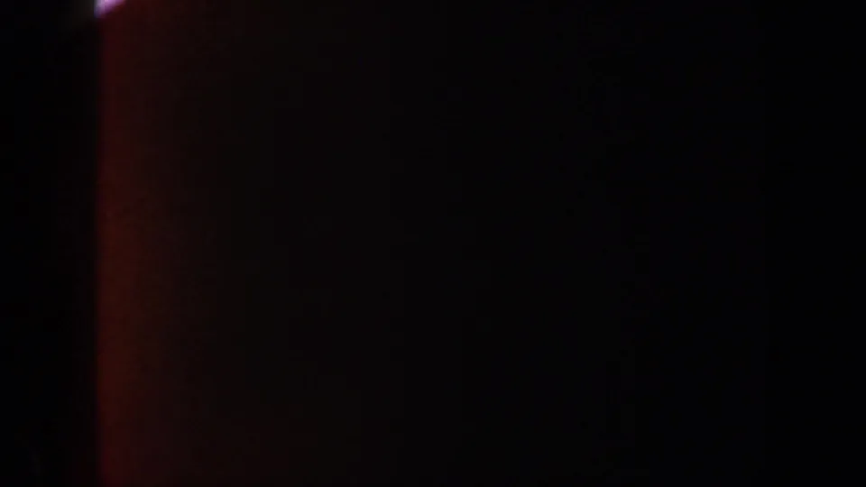 1962 New York 8mm frame showing dim orange light against a mostly black field with soft grain and uneven exposure.