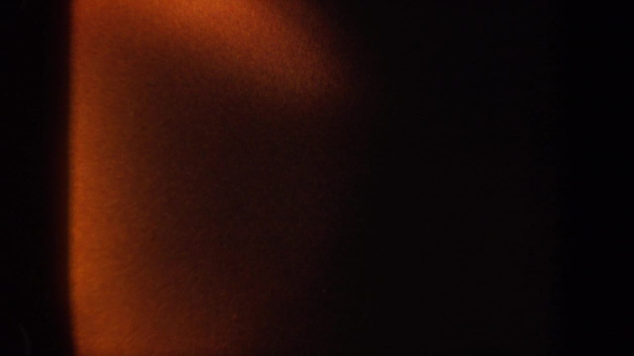 1962 New York 8mm frame with a warm orange column of light fading into deep black shadow.