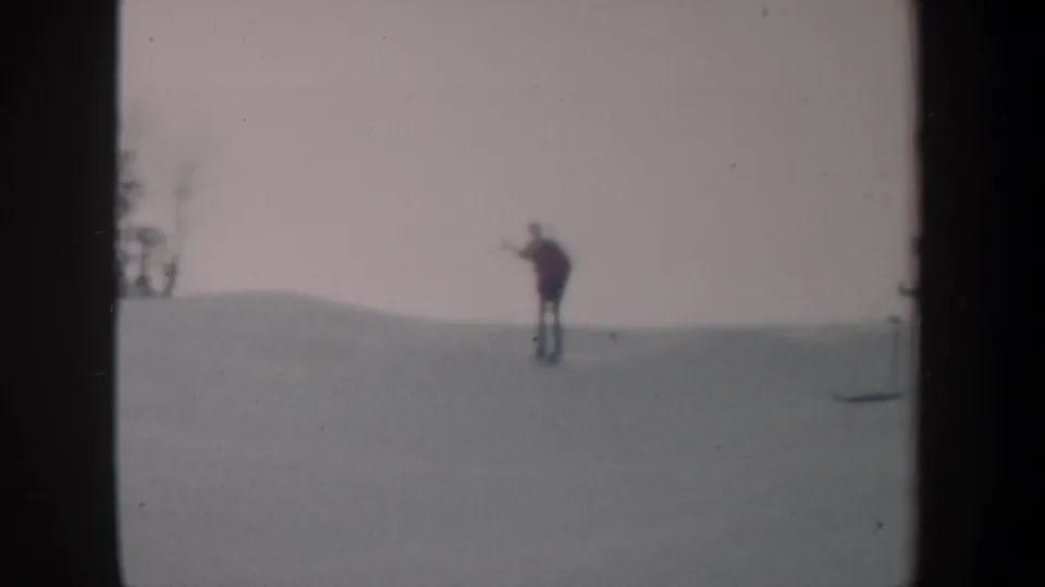 A distant skier appears on a snow-covered slope in the supplied 1962 New York winter recreation footage.