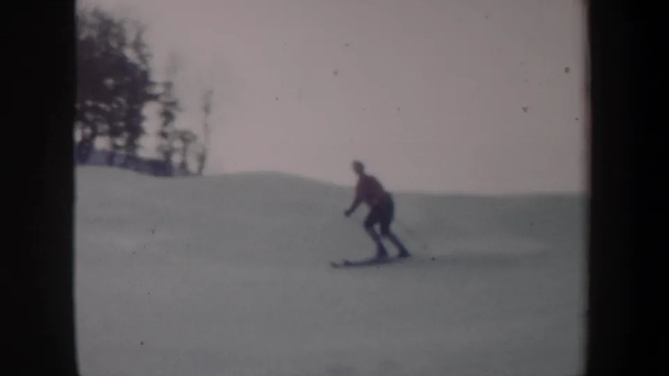 1962 New York 8mm frame showing a distant skier in a red jacket moving downhill across an open snowy slope.