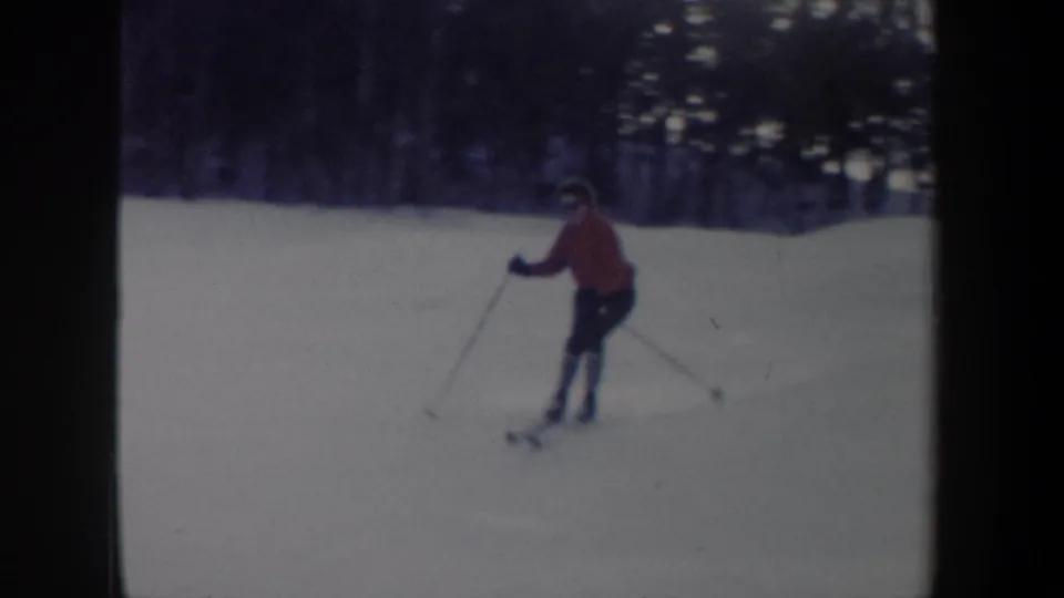 1962 New York home-movie frame of a skier in red moving across a snowy run with poles visible.