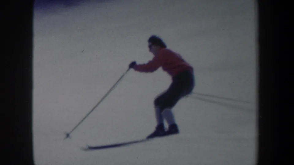 Closer 1962 New York 8mm frame showing the skier leaning forward into a turn with poles and skis visible.