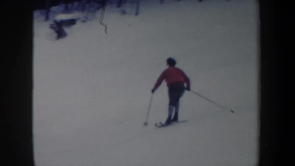 1962 New York 8mm frame showing the skier from behind as they continue downhill across open snow.