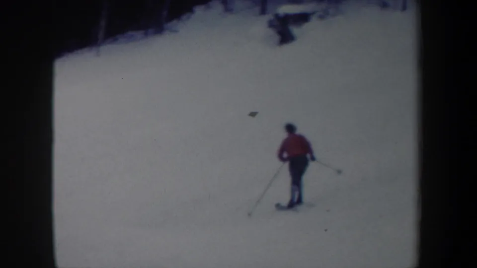 1962 New York 8mm frame showing a distant skier in a red jacket with poles on a bright snowy slope.