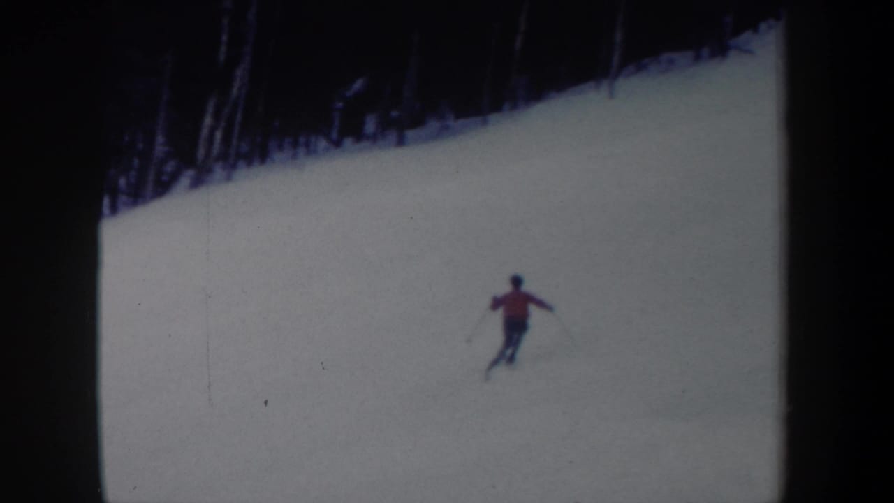 1962 New York 8mm frame with a red-jacketed skier moving downhill across a snow-covered slope.