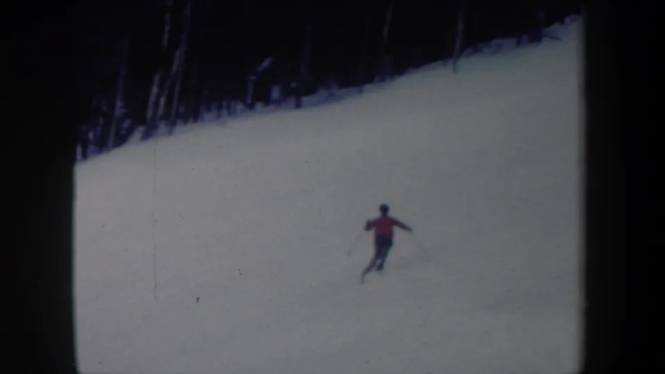 1962 New York 8mm frame with a red-jacketed skier moving downhill across a snow-covered slope.