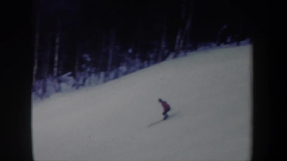 1962 New York 8mm frame showing the skier lower on the slope, leaning into the downhill run.