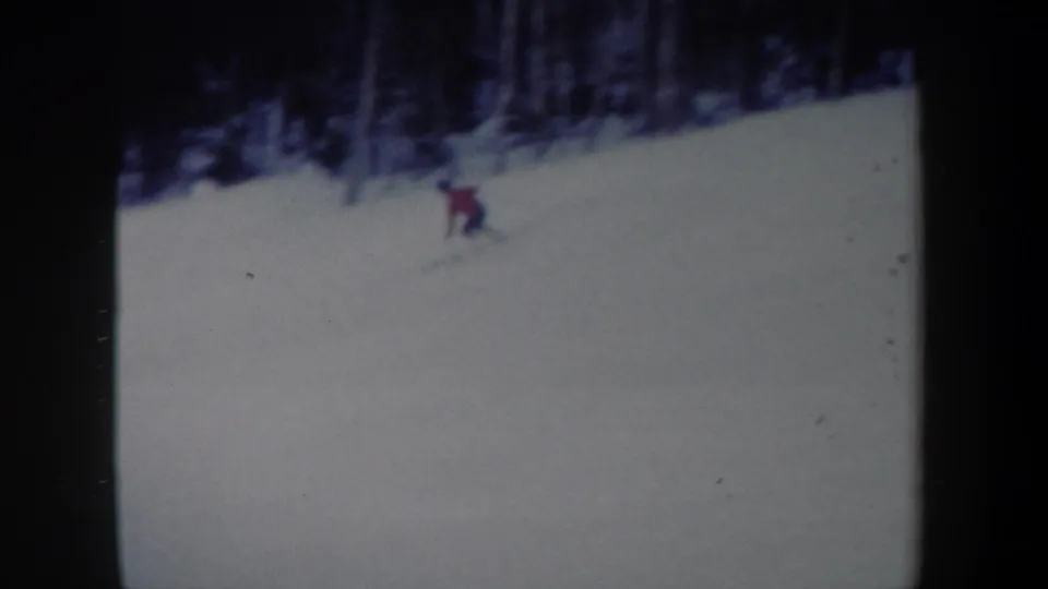 A soft 8mm frame from 1962 New York showing the skier lower on the hill, partly blurred by motion against the broad snow surface.