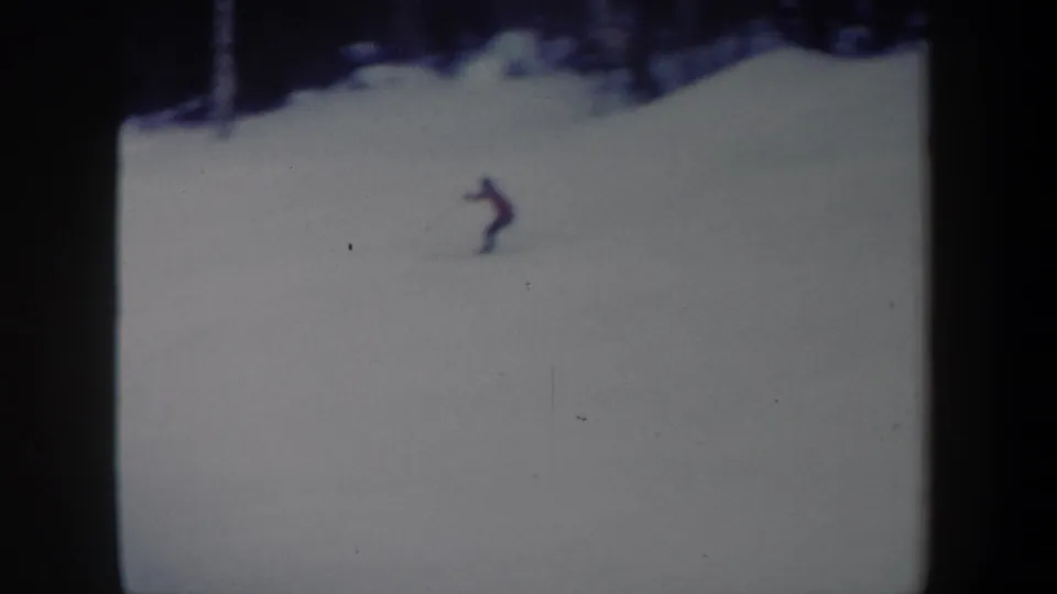 Final 1962 New York 8mm frame with the lone skier moving across the open snow, seen small against the slope and dark film borders.