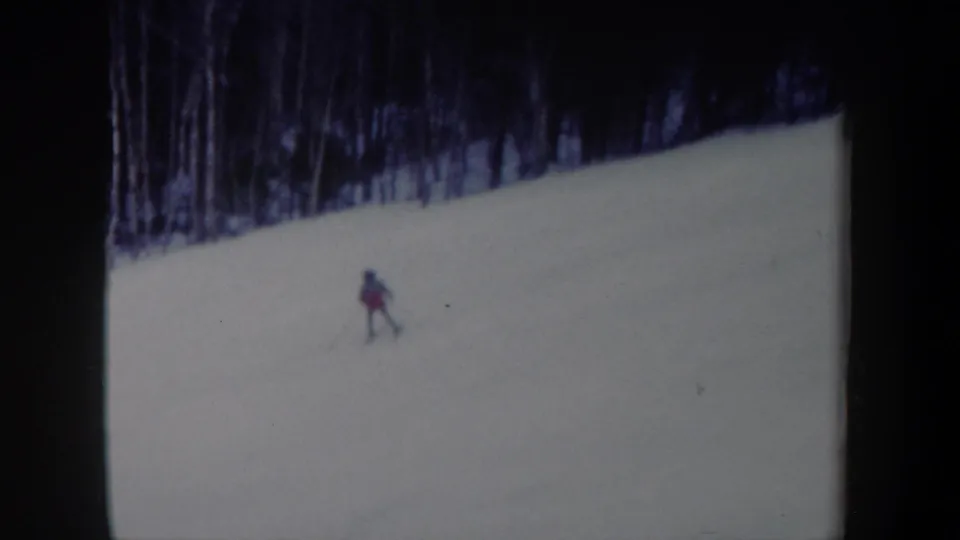 A lone skier continues across the snowy New York hillside, small in frame against the open slope.