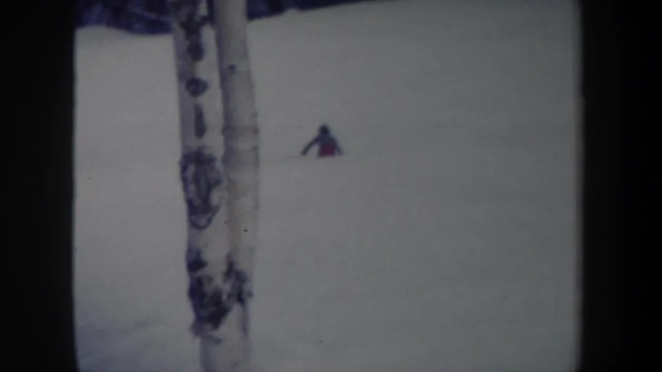 1962 New York 8mm frame with a distant skier on snow and a birch trunk in the foreground.