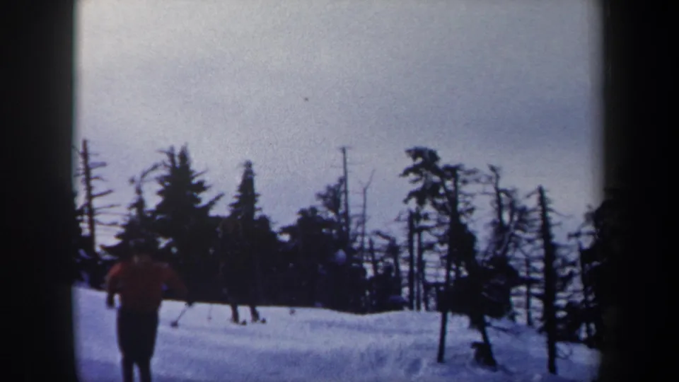 A person in a red jacket is visible on a snowy forest slope in 1962 New York 8mm ski footage.