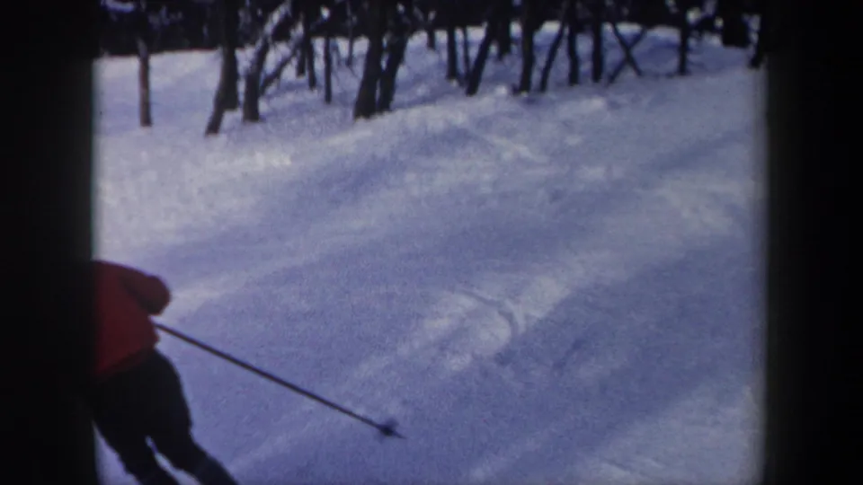 1962 New York 8mm frame with the skier partly cut off at frame edge while moving across a snowy wooded slope.