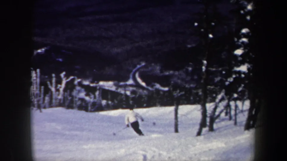 1962 New York 8mm frame showing a skier moving downhill through a snowy forested slope.
