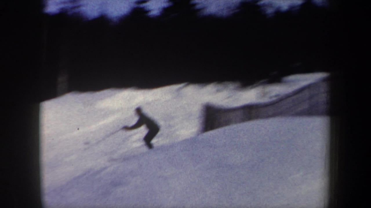 Skier turning on a snowy slope near low fencing.