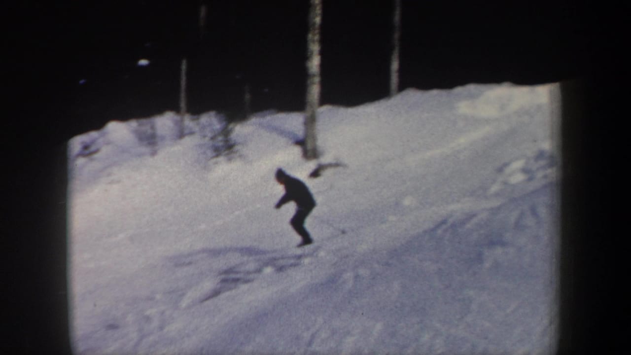 Distant skier moves downhill across a snowy slope near trees.