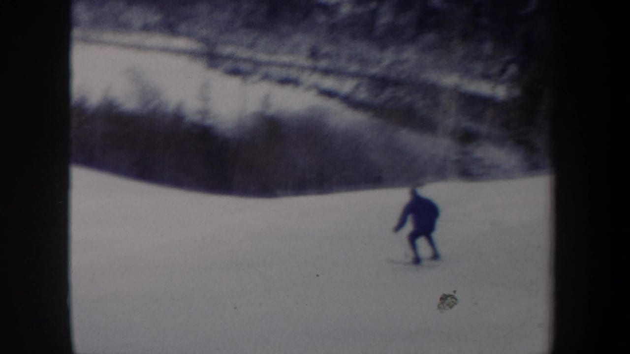 A distant skier in dark clothing moves downhill on a snowy New York slope in 1962 home-movie footage.