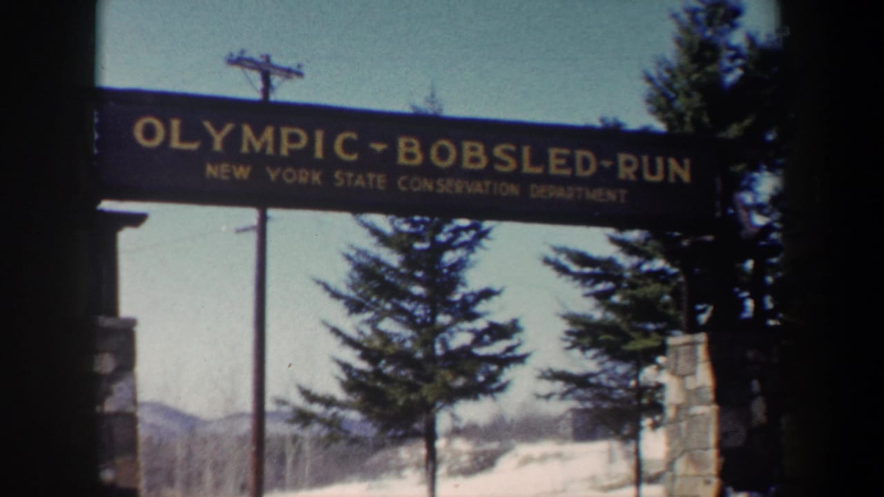 Wooden Olympic Bobsled Run sign above a snowy entrance with trees and stone pillars.
