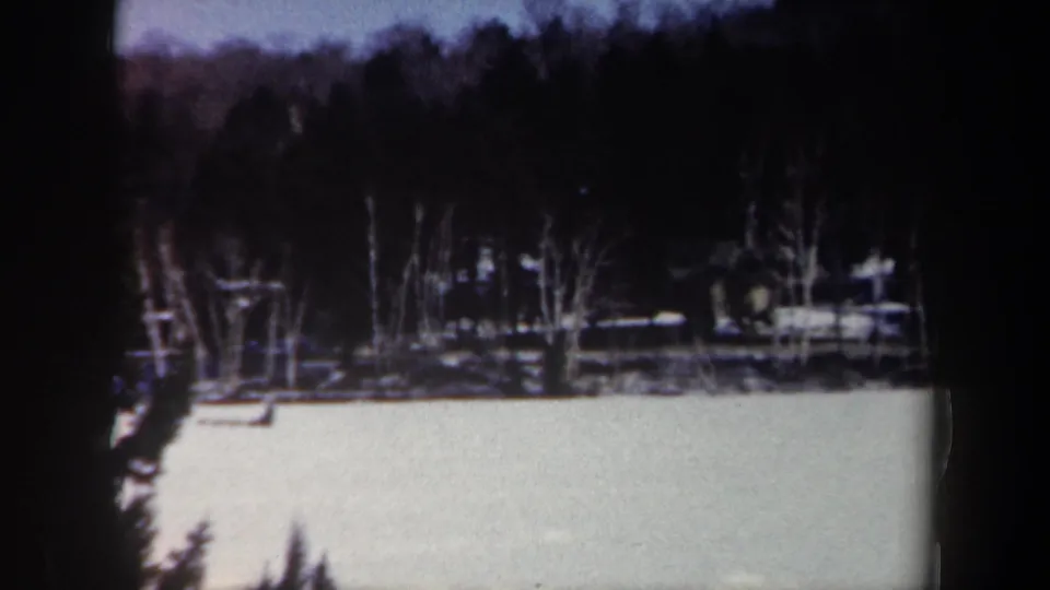 Soft 8mm winter view from New York in 1962, showing snowfield, trees, hillside, and a distant structure.