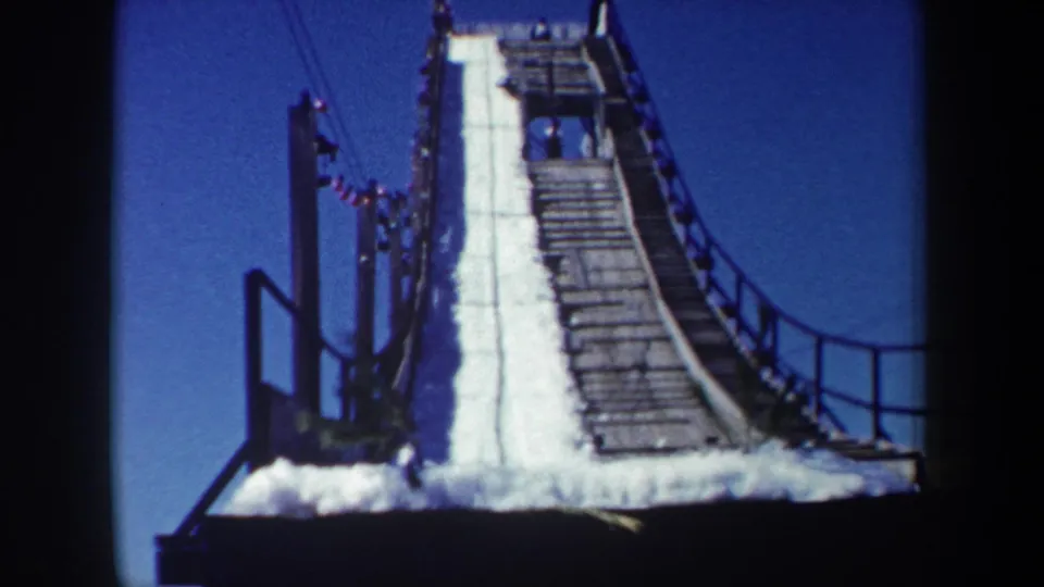 1962 New York frame showing the steep upper ramp, snow track, wooden slats, side railings, and small figures near the top.