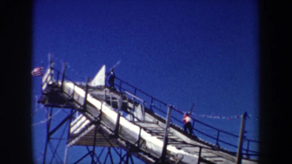 1962 New York 8mm frame showing an American flag at left and two men on a steep railed metal walkway.