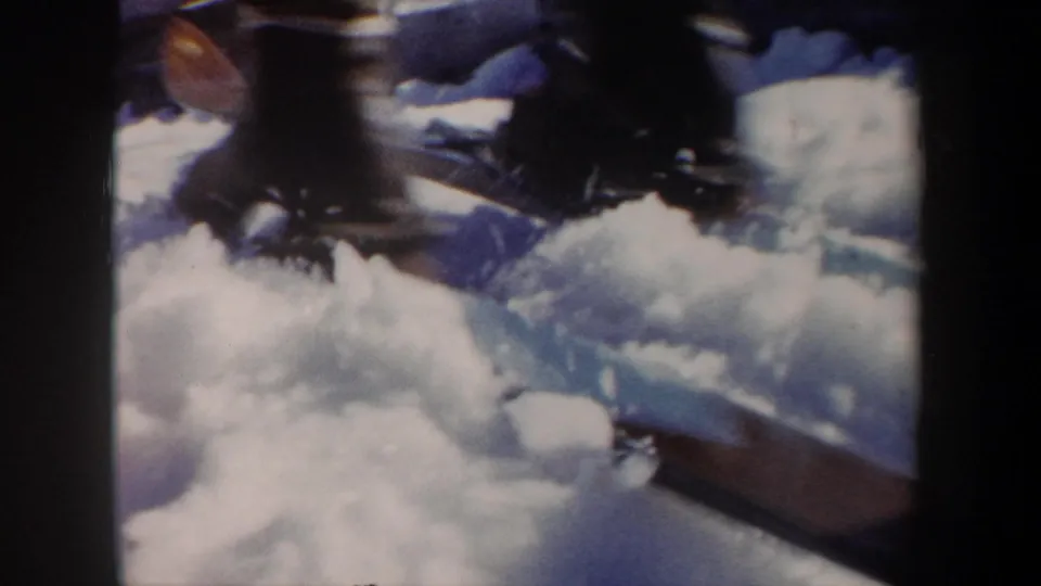 Soft 8mm close-up of piled snow and indistinct foreground equipment or clothing near the New York winter sports scene.