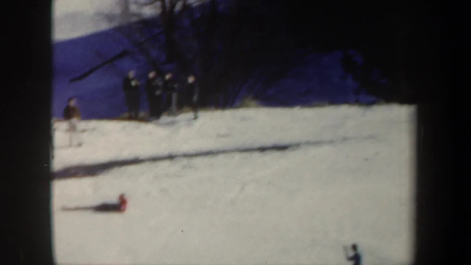 1962 New York 8mm frame showing a skier down on the snow after a fall, with a small group watching from higher on the slope.