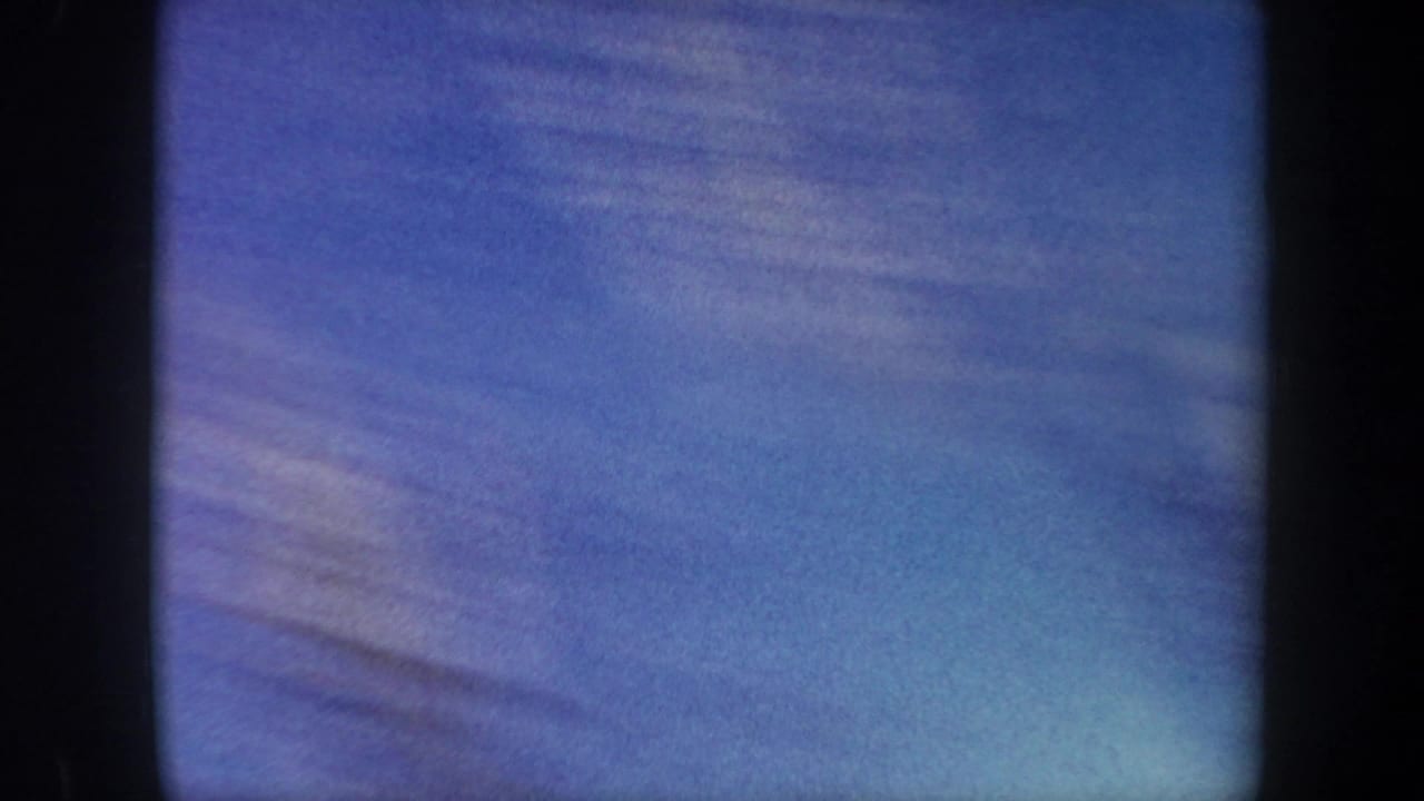 Opening 8mm frame from the 1962 New York ski-jump clip, showing mostly blue sky or snow-toned blur with dark gate edges.