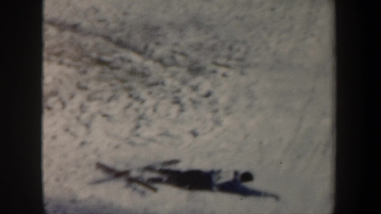 1962 New York 8mm frame showing a skier down on a snowy jump slope, with soft focus and dark gate edges.