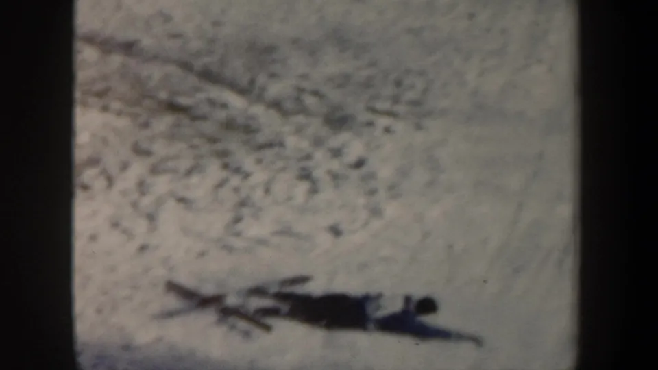 1962 New York 8mm frame showing a skier down on a snowy jump slope, with soft focus and dark gate edges.