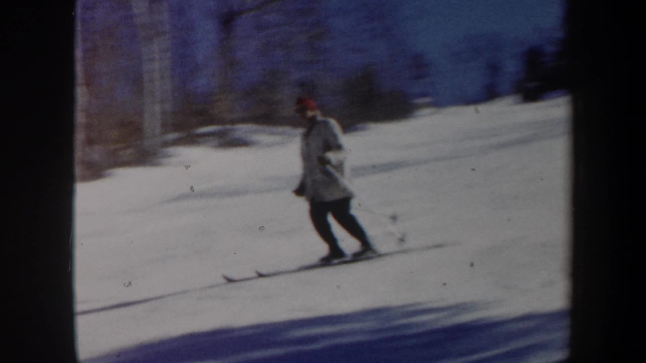 Skier glides across a bright snowy slope using ski poles.
