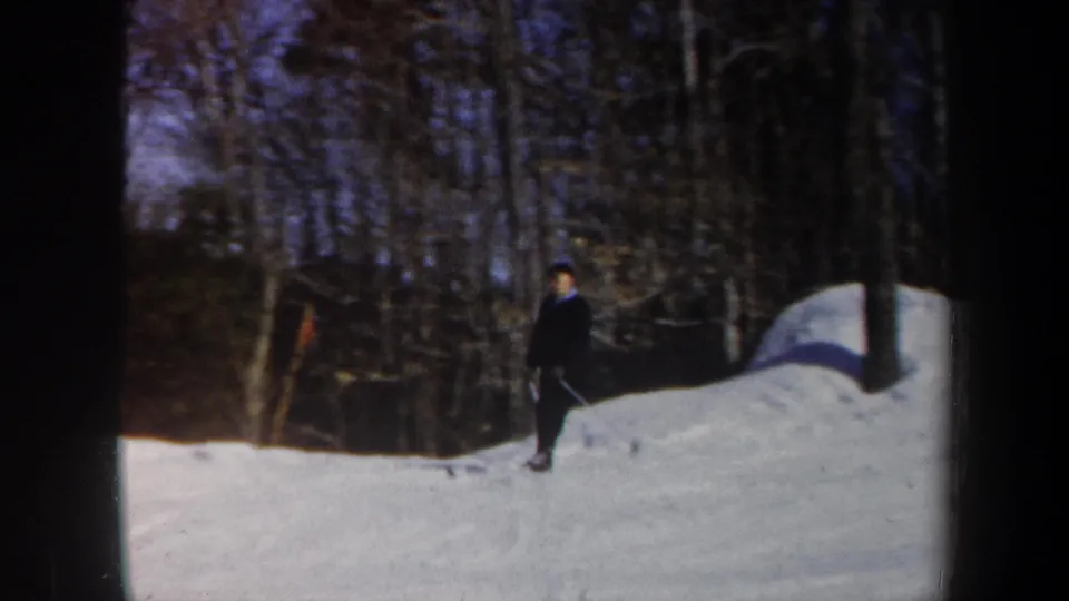 1962 Vermont home-movie frame showing a skier near the treeline on a gentle snow-covered slope.