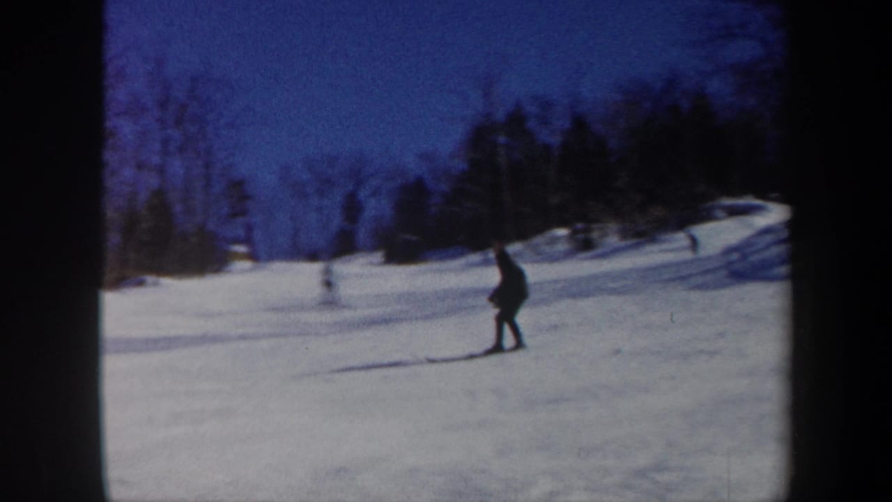 1962 Vermont 8mm frame showing a distant skier in dark clothing crossing a snowy wooded slope.