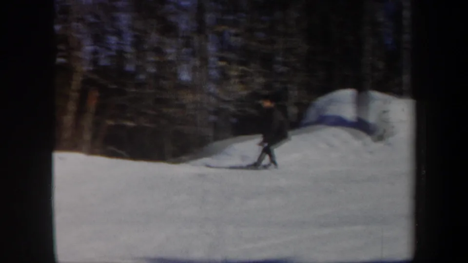 1962 Vermont home-movie frame with a skier nearing the wooded edge of a snowy slope.