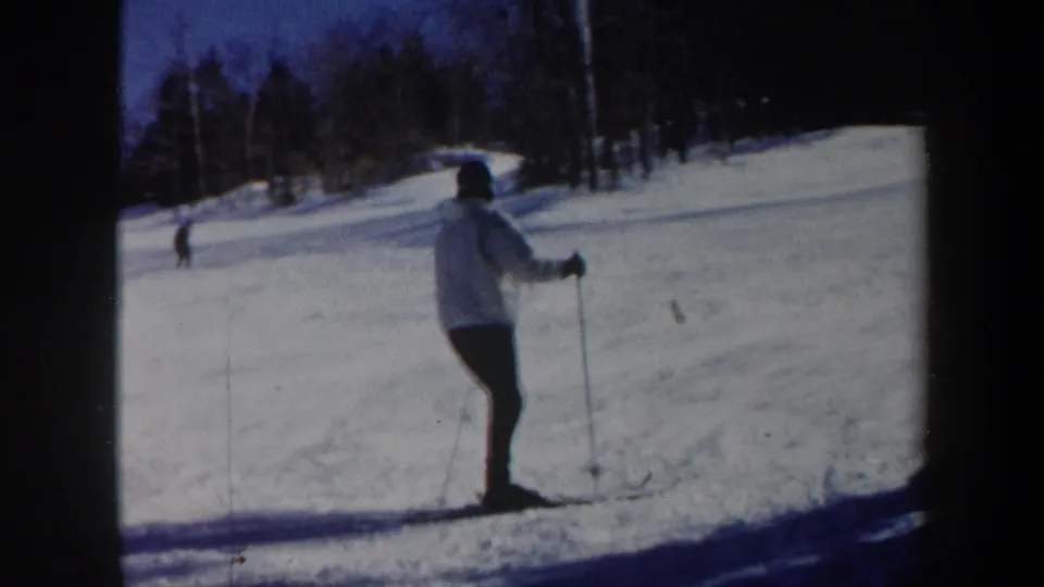 1962 Vermont ski footage frame showing a skier on the right side of a snowy run with wooded background.