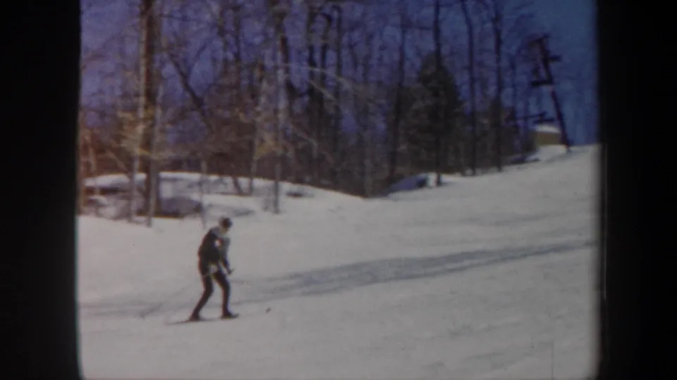 1962 Vermont frame with a skier practicing on a bright snowy hillside near leafless trees and a visible utility pole.