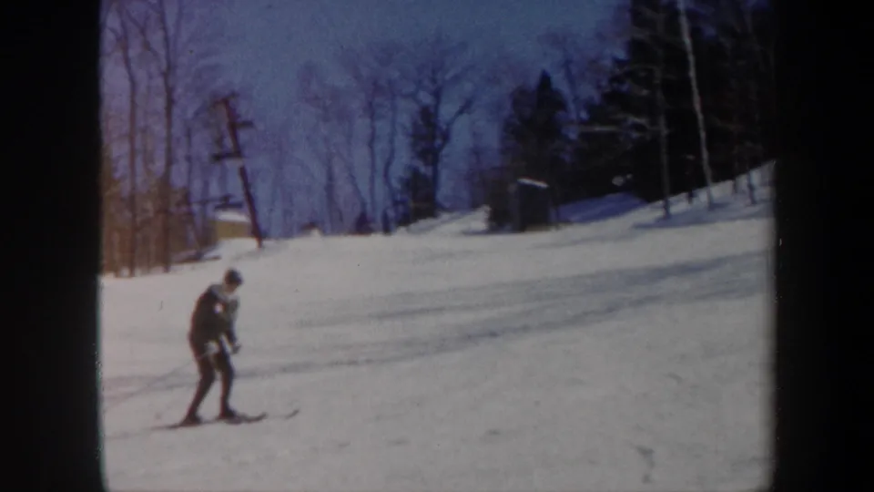 A 1962 Vermont 8mm frame shows the skier leaning forward during practice on a gentle wooded slope.