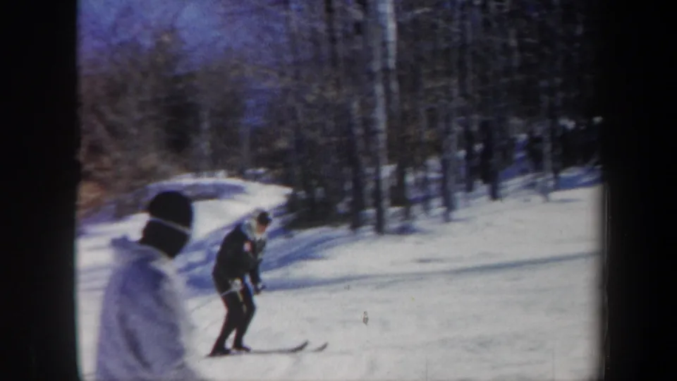 1962 Vermont 8mm frame showing a skier using poles on a snowy slope, with bare trees and another winter-clad figure nearby.