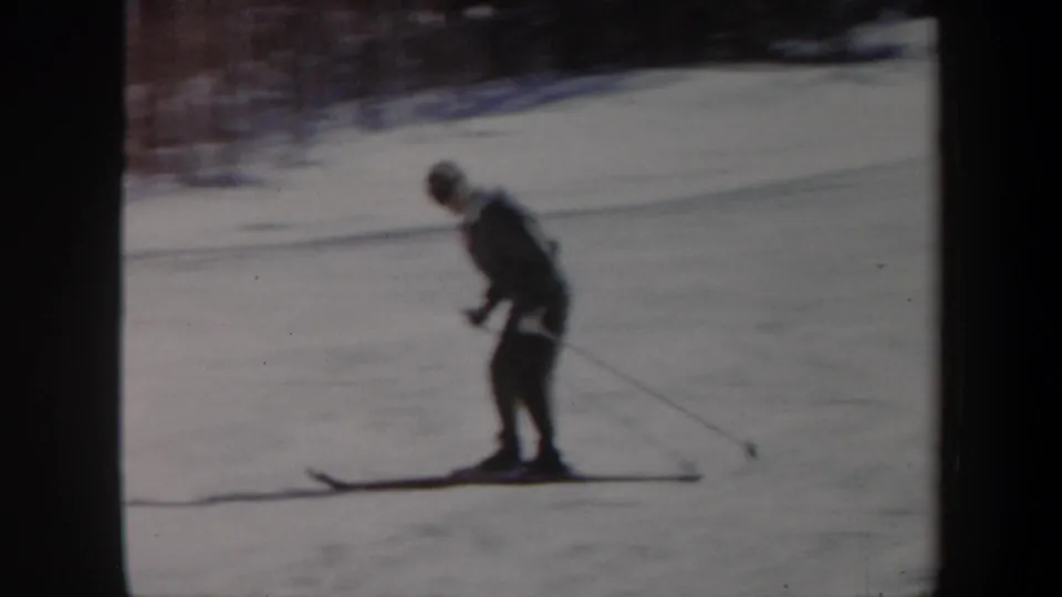 1962 Vermont 8mm frame showing the skier in side view on the snow, with motion blur and soft winter light.