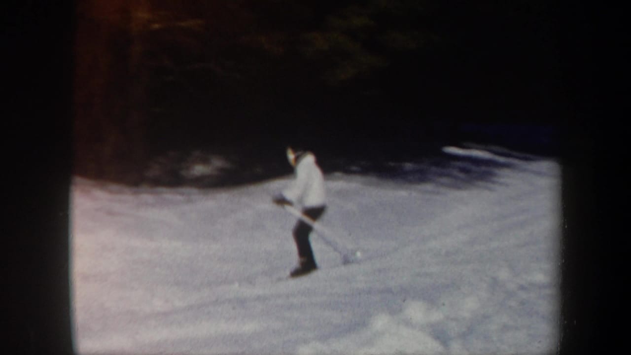 A skier in a light jacket and dark pants practices with poles on a snowy Vermont slope, filmed in 1962 on 8mm.