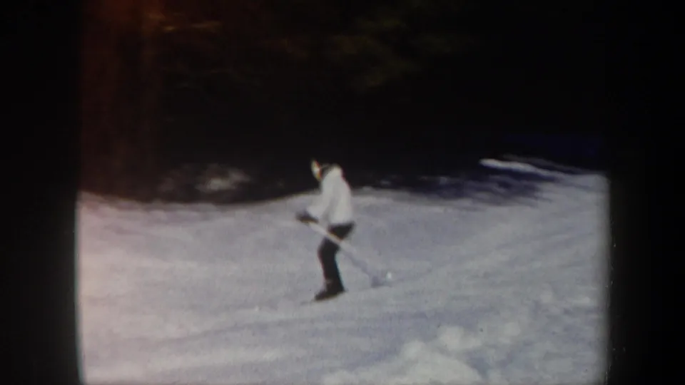 A skier in a light jacket and dark pants practices with poles on a snowy Vermont slope, filmed in 1962 on 8mm.