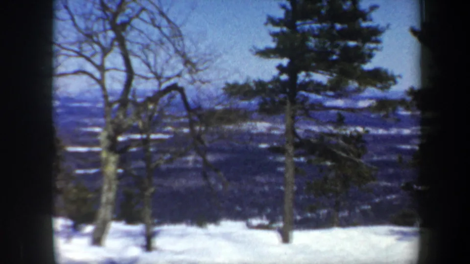 A scenic 1962 Vermont winter view shows bare trees, evergreens, snow patches, and distant hills in soft 8mm color.