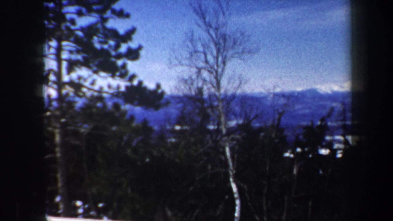 Vermont 1962 home-movie frame showing a snowy wooded mountain view with distant peaks and heavy film borders.