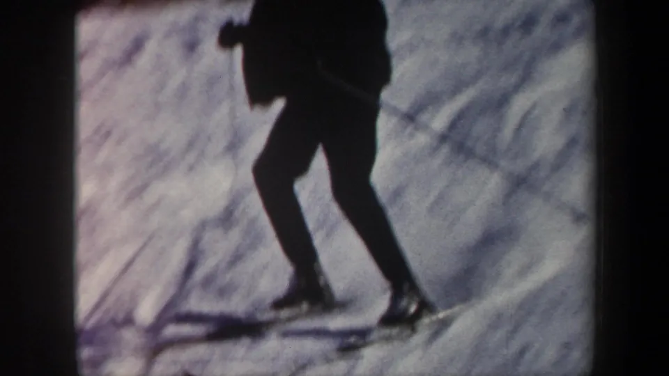 Close 8mm frame showing the skier's legs, skis, and poles cutting across a snowy Vermont slope.