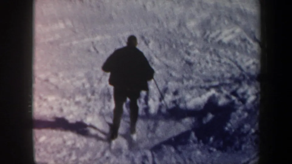 A distant skier in dark winter clothing crosses the snowy Vermont slope in faded 8mm color.