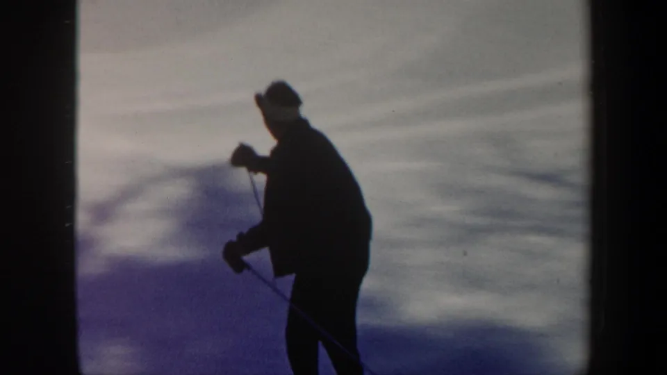 1962 Vermont 8mm frame showing a skier in dark clothing on a snow-covered slope, partly silhouetted by winter light.