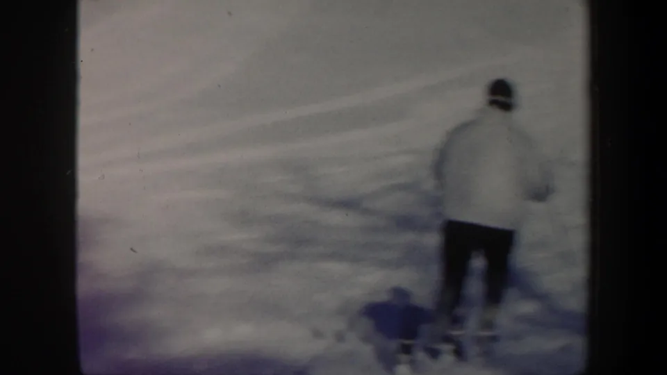 1962 Vermont 8mm frame showing a skier in a light jacket seen from behind while moving downhill over soft snow.