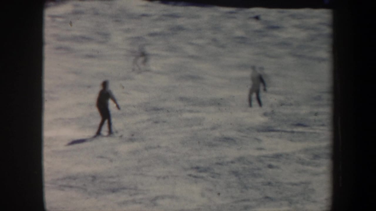 Several skiers are spaced across an open snowy slope.