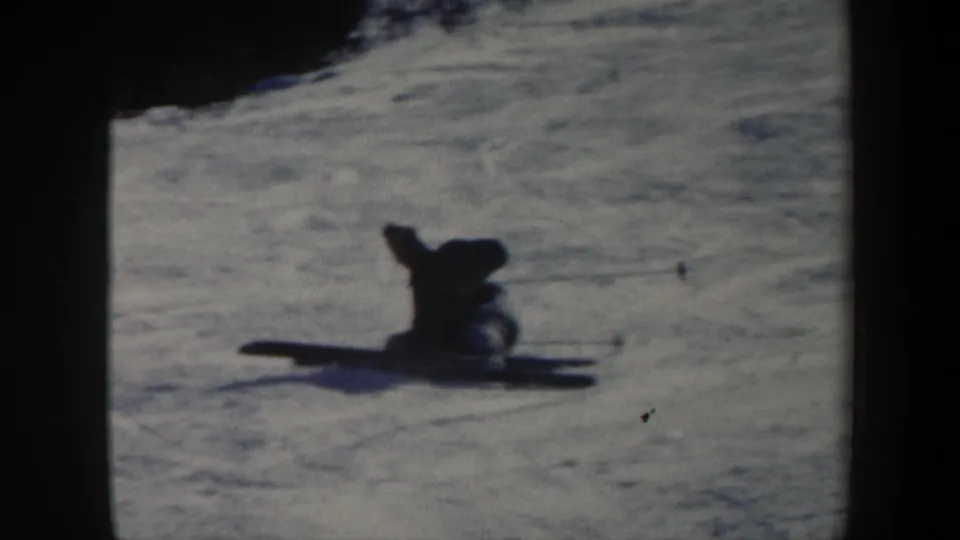 Adult skier rests in the snow after falling on a Vermont slope in 1962 8mm home-movie footage.