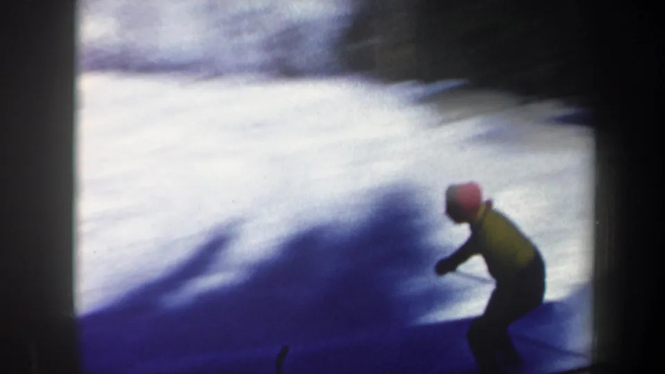 1962 Vermont home-movie frame with the skier partly silhouetted near the lower edge of a snowy forest slope.